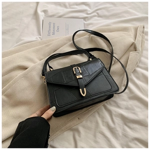 Détail d'un sac noir géométrique en similicuir avec boucle dorée en fer à cheval