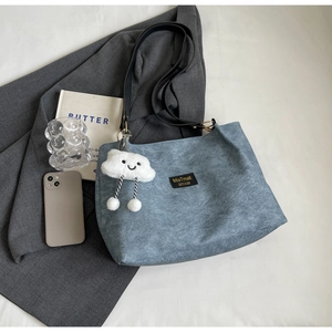 Blue matte textured tote bag with black leather straps and cloud charm accessory