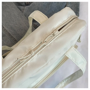 Détail du zip et de la tirette tissée sur un sac fourre-tout léger en toile blanc crème