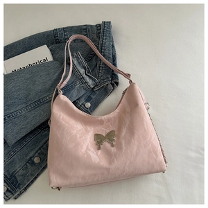 Detailed view of pink glossy patent leather shoulder bag with silver butterfly ornament