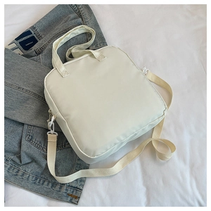 Détail d'un sac fourre-tout en toile blanc crème avec bandoulière réglable sur une veste en jean