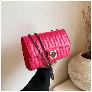 Detailed close-up of rose red quilted leather bag with clover-shaped metal lock and chain