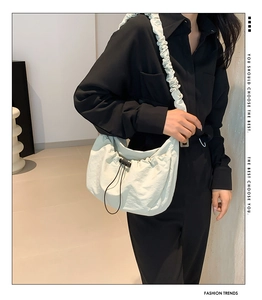 Detail of cream white pleated hobo bag with drawstring and scrunched strap on model