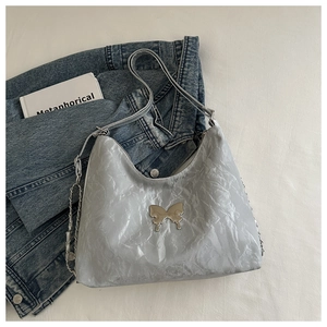 Close-up of metallic silver pleated tote with metal butterfly and chain detail