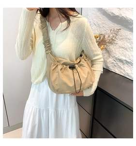 Detail view of beige nylon hobo bag featuring drawstring pleats and ruched cloud shoulder strap