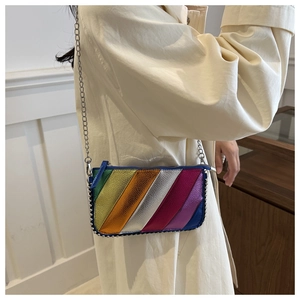 Détail d'un sac bandoulière arc-en-ciel avec clous argentés porté par un mannequin