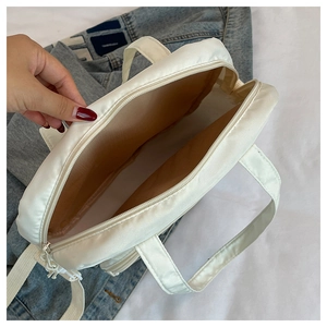 Gros plan de l'intérieur spacieux du sac fourre-tout en nylon blanc avec doublure marron et zip