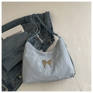 Detail of light blue pleated shoulder bag with silver butterfly metal ornament and chain