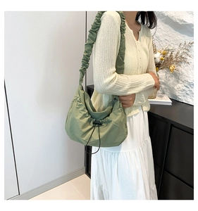 Detail of green ruched nylon shoulder bag with drawstring closure and wide strap
