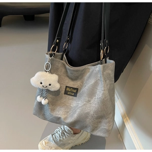 Detail view of grey canvas tote bag with black straps and plush cloud charm accessory