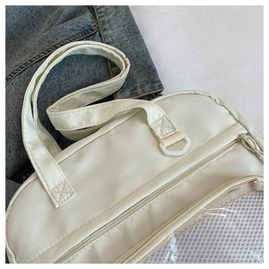 Détail du sac fourre-tout en toile beige avec fermeture éclair et poche en filet latérale