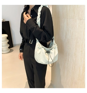 Detail of the ruffle shoulder strap and drawstring closure on the nylon crescent bag