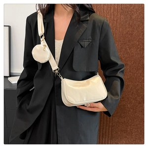Detail of cream crossbody bag with wide strap and mini pouch shown on model