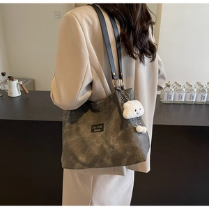 Detail of vintage canvas tote with leather straps and cloud charm on a model's shoulder
