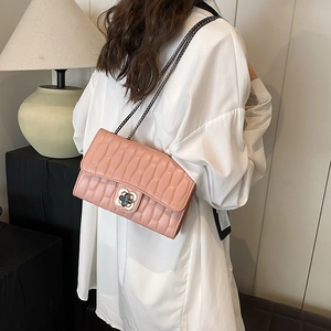 Pink quilted leather crossbody bag with clover buckle and chain strap on a model