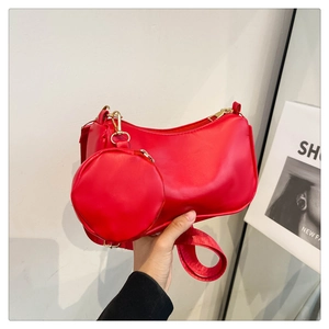Detailed view of red baguette bag with matching circular coin purse and gold hardware