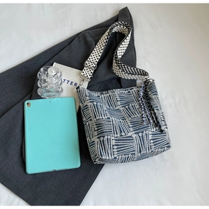 Detail of blue and white checkered canvas tote bag with jacquard strap and fringe tassel