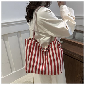 Close-up of durable canvas tote bag with red and white stripes worn on shoulder