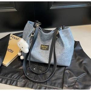 Detail of grey canvas tote bag with black leather straps and cloud charm accessory