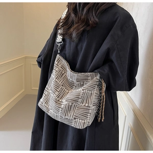 Detail of checkered canvas tote bag with adjustable strap and side tassel decor