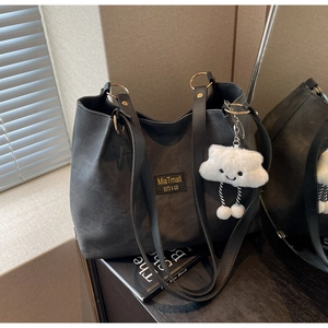 Detail of black tote bag with gold ring hardware and cute white plush cloud charm