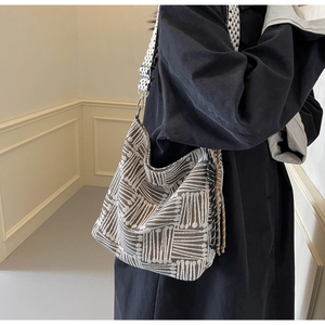 Detailed view of the woven checkered texture and silver metal hooks on a canvas tote bag