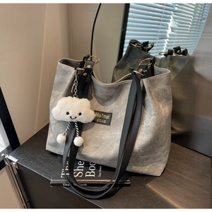 Detail of grey canvas tote bag with black shoulder straps and cloud charm accessory