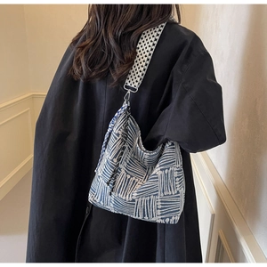 Close-up of checkered canvas tote bag featuring a blue woven pattern and plaid strap
