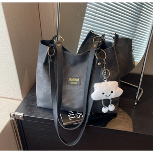 Detail of black tote bag with gold ring connectors and cute cloud charm accessory