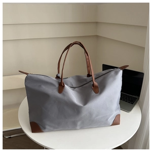 Detail of high-capacity grey nylon tote bag with leather handles and laptop accessory