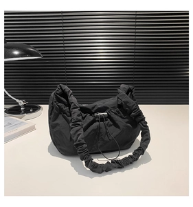 Detail of minimalist black nylon shoulder bag with pleated straps and drawstring closure