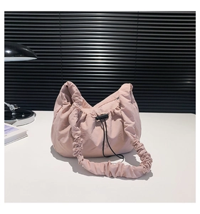Close-up of light pink drawstring nylon bag with scrunched handle on a desk