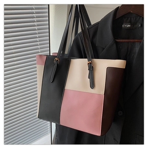 Detail of color-block tote bag featuring matte leather texture and gold buckle accents