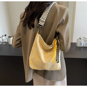 Detail of yellow checkered canvas hobo bag with a woven strap and decorative drawstring