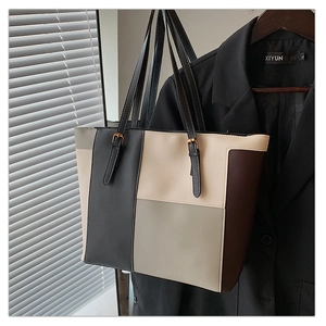 Detail view of large color-block tote bag hanging on blazer against shutter background
