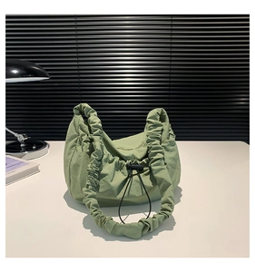 Detail of sage green nylon shoulder bag featuring pleated elastic strap and drawstring toggle