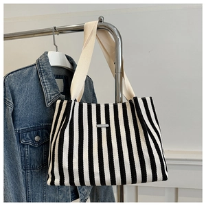 Détail d'un sac cabas en toile rayée avec texture tissée et plaque en métal argenté