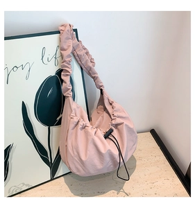 Detail of pink nylon dumpling bag with drawstring closure and pleated shoulder strap design