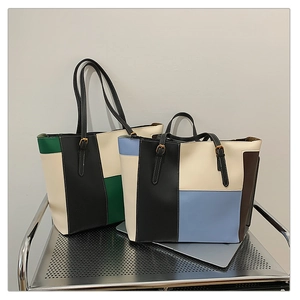 Close-up of geometric color-block leather tote bags with metal buckles and long shoulder straps