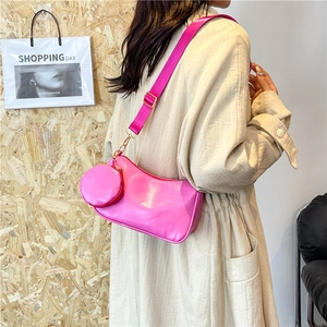Pink shoulder bag with matching round coin purse and wide strap on model back