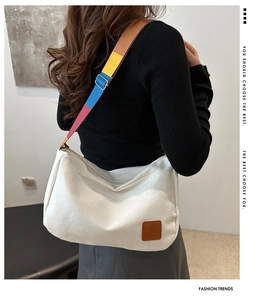 Detail of adjustable colorful striped woven shoulder strap on a white canvas crossbody bag