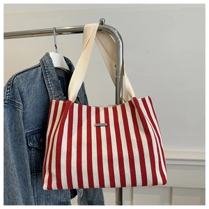 Détail du cabas en toile rayé rouge et blanc accroché avec une veste en jean sur un support