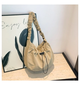 Detail of khaki pleated nylon underarm bag with drawstring buckle and elastic shoulder strap
