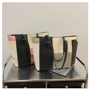 Detail view of two large color-block tote bags in pink and grey on a silver cart