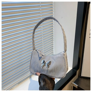 Detail of silver pleated bag featuring a metallic butterfly buckle and Y2K aesthetic