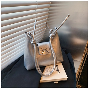 Detail of silver metallic shoulder bag showing leather texture and decorative bow knot