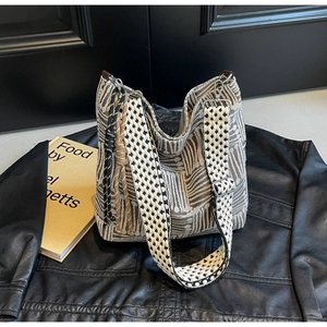 Detail of canvas tote bag featuring wavy texture and checkerboard woven shoulder strap