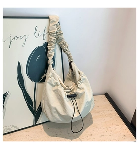 Close-up of beige nylon shoulder bag with drawstring detail and ruffled strap