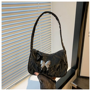 Detail of black pleated shoulder bag with a silver liquid metal butterfly buckle charm