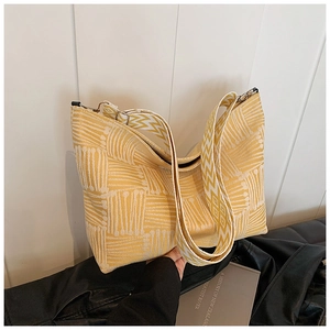 Detail of yellow and white knit tote bag featuring geometric textures and metal hardware